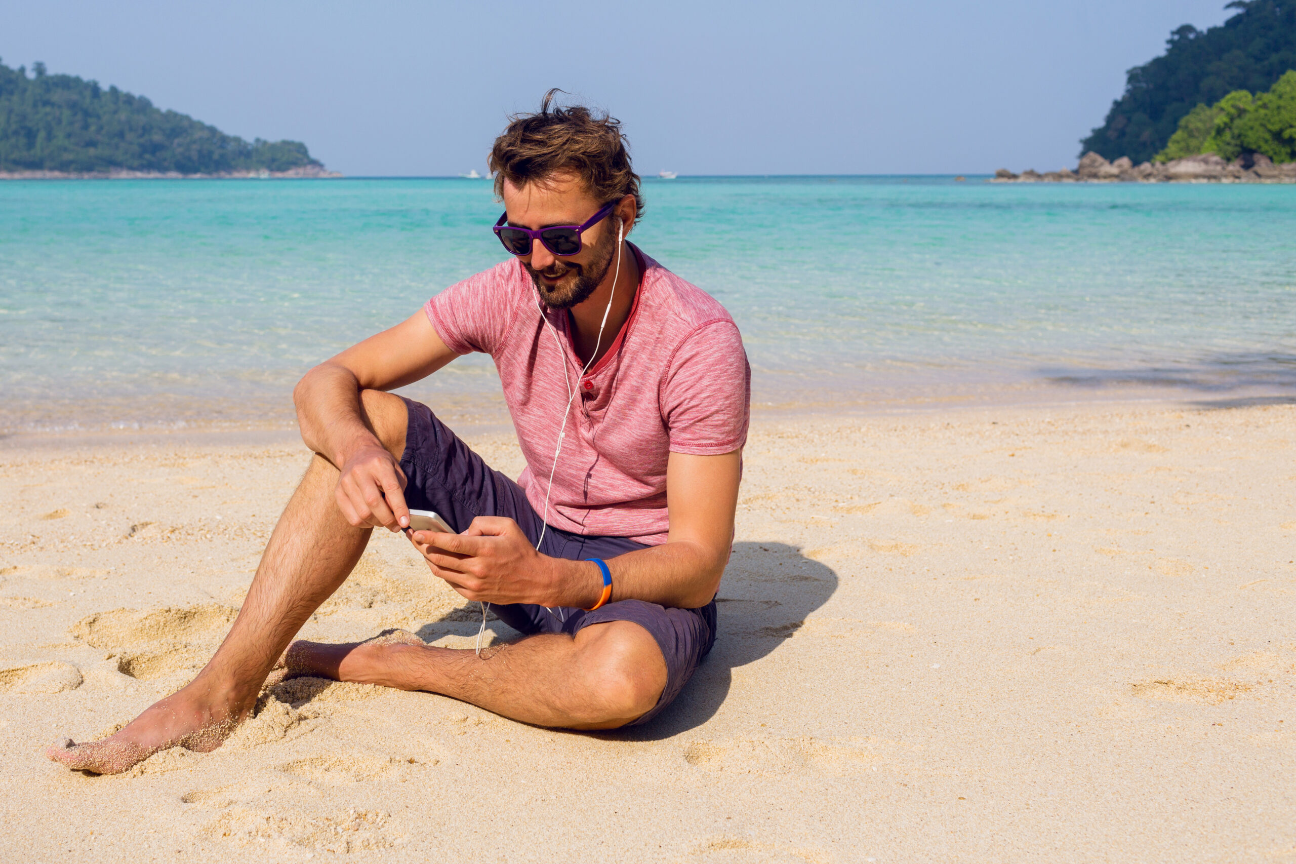 jeune homme sur la plage, naviguant sur son téléphone